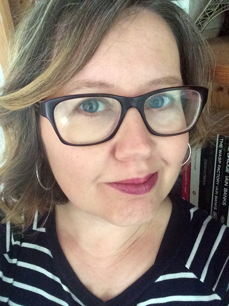 Author Fiona Leitch. A middle-aged blonde woman with shoulder length hair and dark rimmed glasses and a pink-lipsticked smile.
