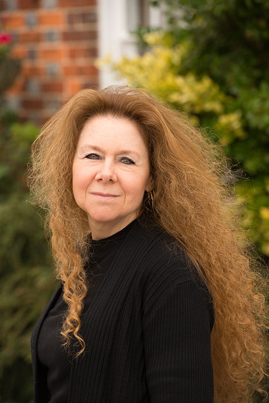 Author photo: Smiling woman with long red hair wearing a black jumper 